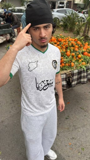 Woman wearing black Syrian football jersey on city street at night